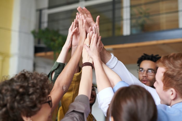 A group of people in business clothes doing a group high five.