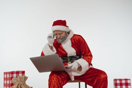 Santa Claus looking at a laptop.