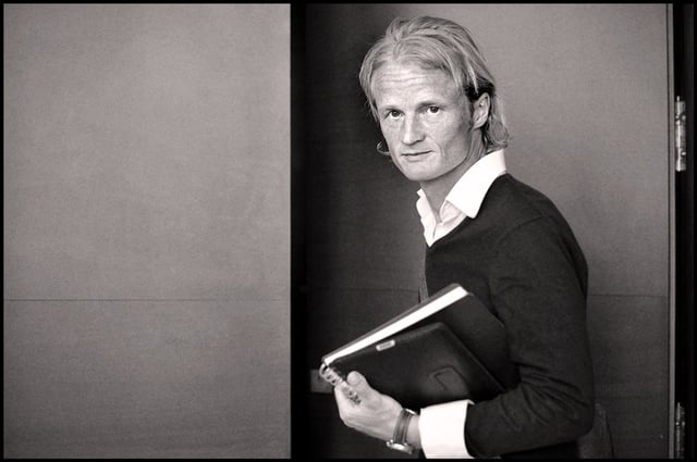 Black and white photo of Anders Ojgaard holding a book