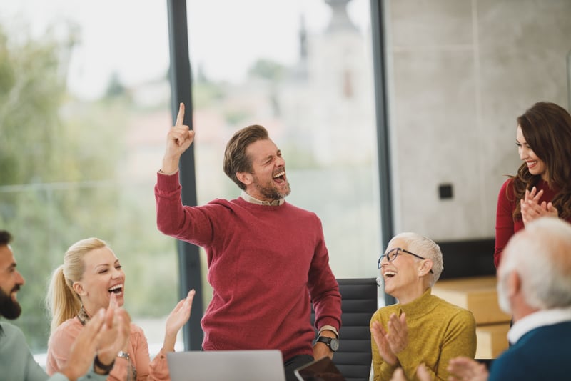 A group of people looking very happy around a laptop.