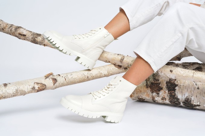 Woman sitting on a tree trunk with white Otter boots 